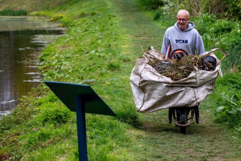 A volunteer clears debris from Barry's Mill's pond