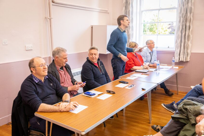 People seated behind table in Errol village hall;