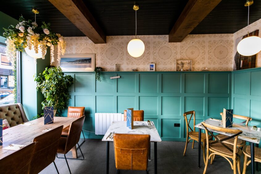 Inside The Ferry Selkie there is turquoise panelling, round lamps hanging from the ceiling and brown leather or wooden chairs.