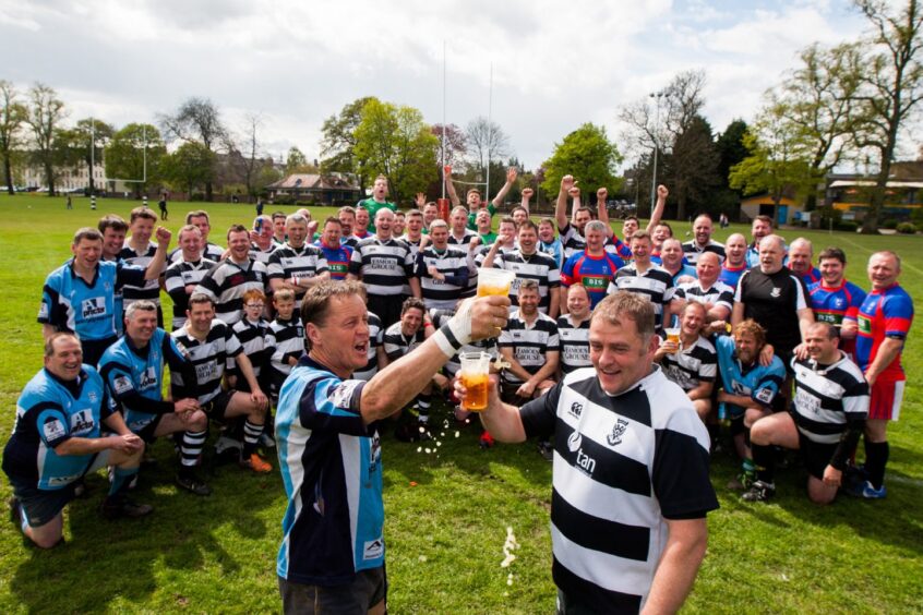 two men raise beer glasses while the other golden oldies gather behind them at the North Inch event in 2015. 