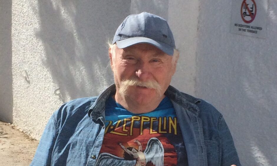 Scott Goring smiling in denim cap and shirt with Led Zeppelin t shirt