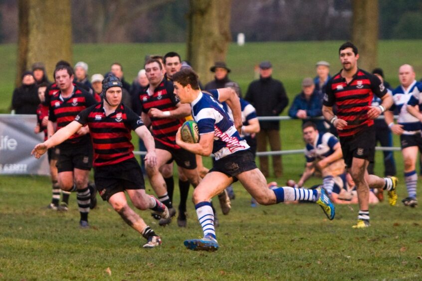 a man runs with the ball while the other team tries to close him down