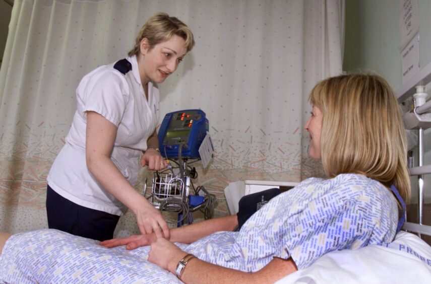Senior charge nurse Margaret Park talks to a patient who is lying in bed