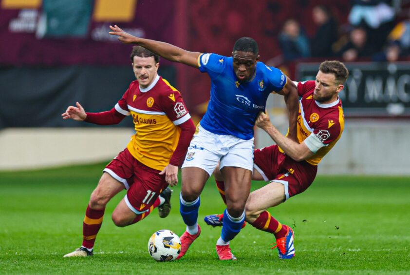 Uche Ikpeazu holds off two Motherwell defenders.