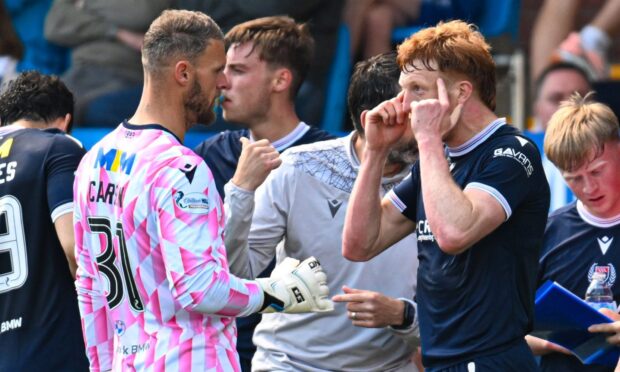 Simon Murray points to his temples in conversation with Dundee team-mate Trevor Carson.