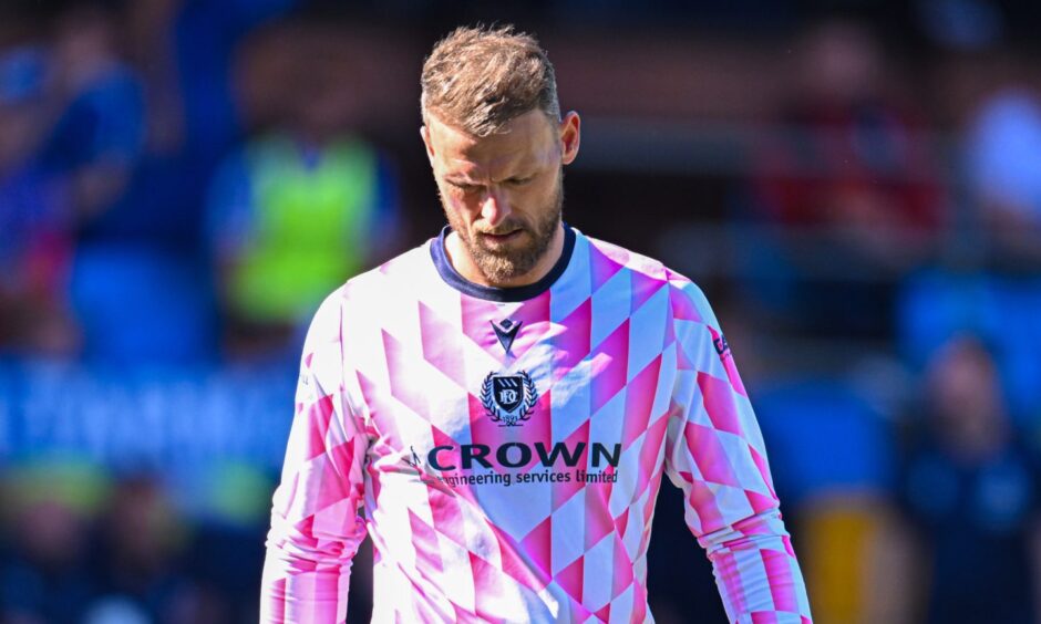 Dundee goalkeeper Trevor Carson looks down at the ground in pensive mood.