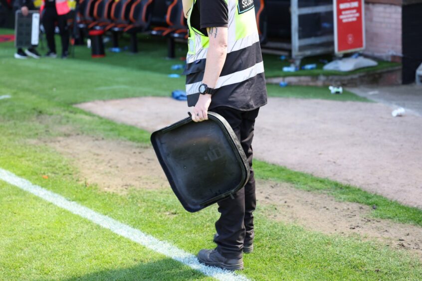 A steward clutches a thrown seat from the Aberdeen section