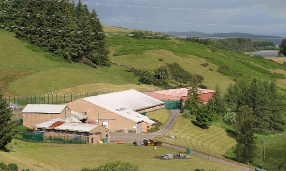 The water treatment plant with reservoir behind and trees and hills around.