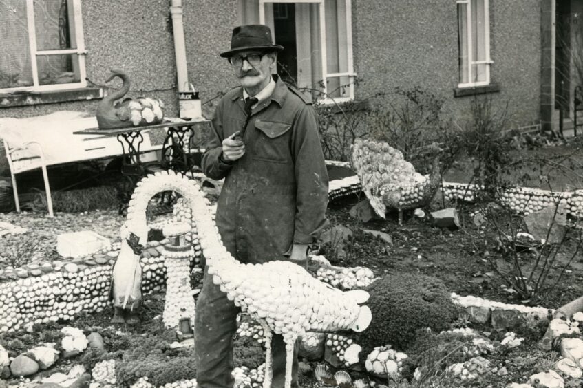 Robert Deasley in the front garden of his home on Duncraig Road in February 1980. He is smoking a pipe and surrounded by statuary.