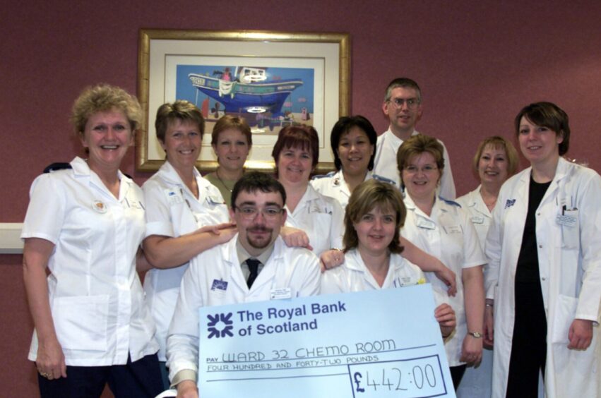 Hospital staff look on as Andy Bell hands over a cheque to chemotherapy charge nurse Debbie Forbes.