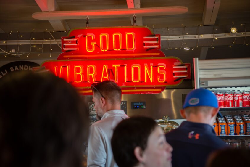 A red neon light sign in a café says Good Vibrations.