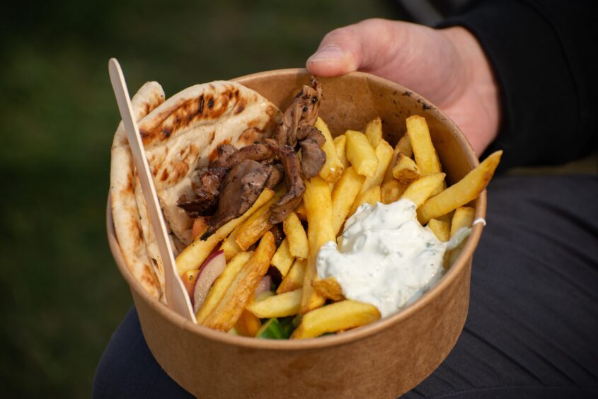 A brown cardboard tub filled with fries, mushrooms, flatbread and a white sauce.