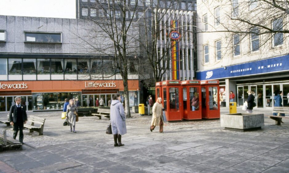 People walking past the red BT telephone boxes outside Boots, C&A and Littlewoods in Dundee city centre in 1987.