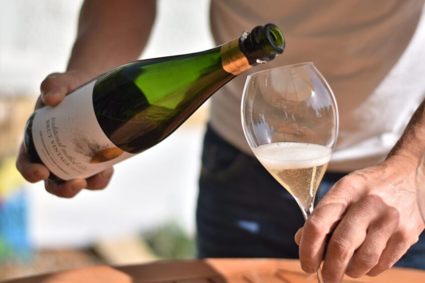 A man pouring a class of cider.