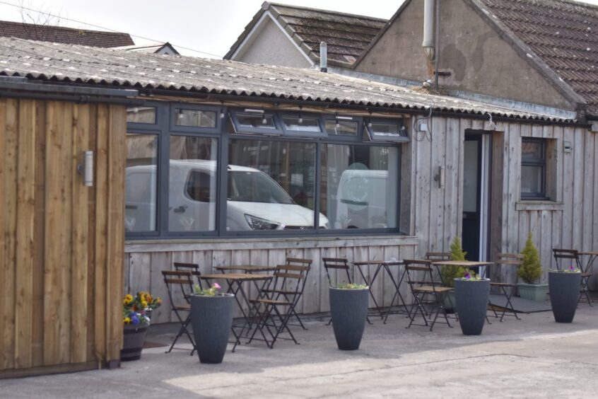 The outside of a café with a seating area.
