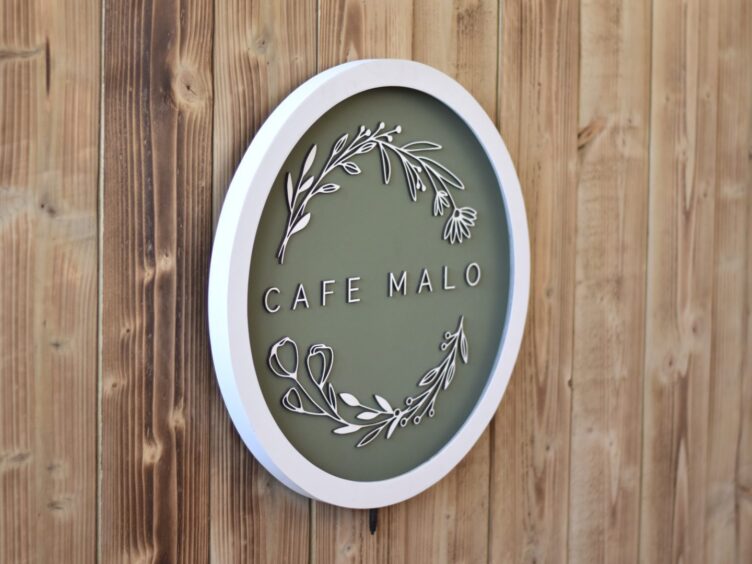 A sign for Café Malo, mounted on wood.