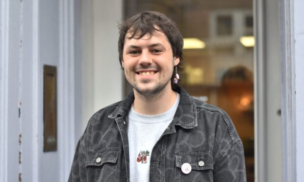 A man smiling in front of a café.