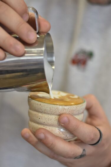 Brodie making latte art as he prepares for his barista competition.