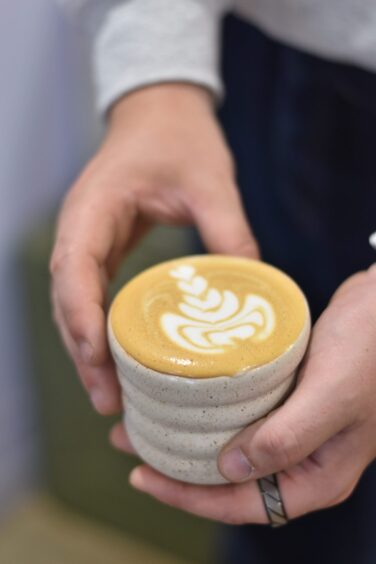 A person holding a flat white made as part of his training for a barista competition.