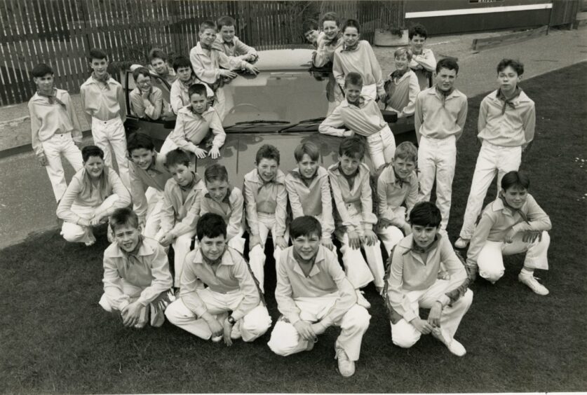 Participants in the Country and Western Gang Show pose for a picture around a car