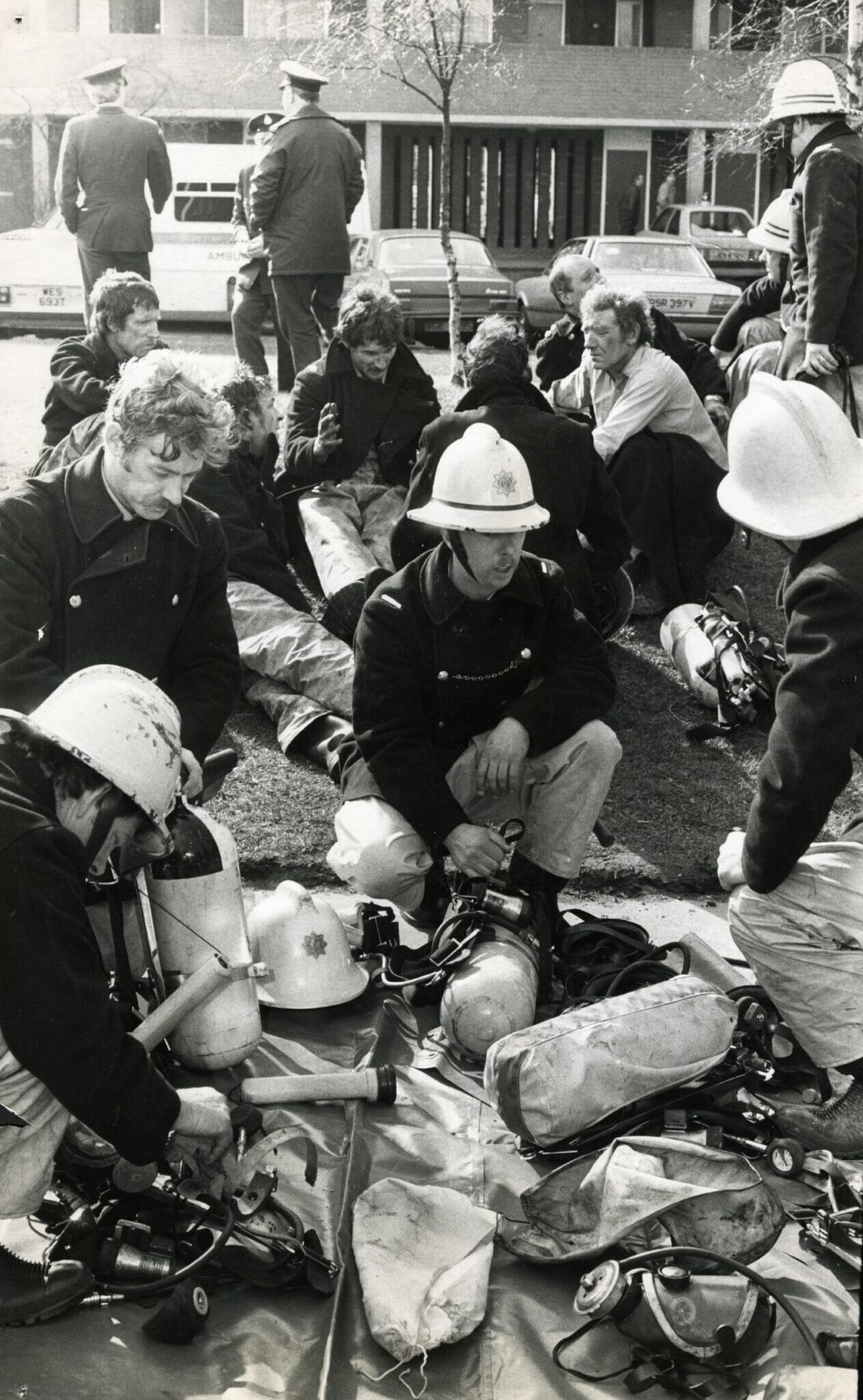 Firefighters kneeling down while gathering their equipment prior to entering the Dundee building.