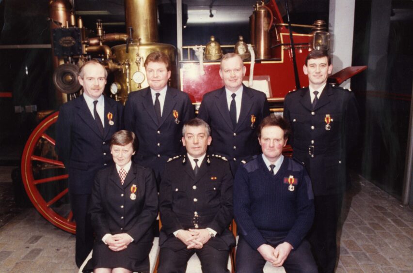 Long service awards recipients at Blackness Road Station in February 1991. They are pictured in front of a vintage red fire engine.