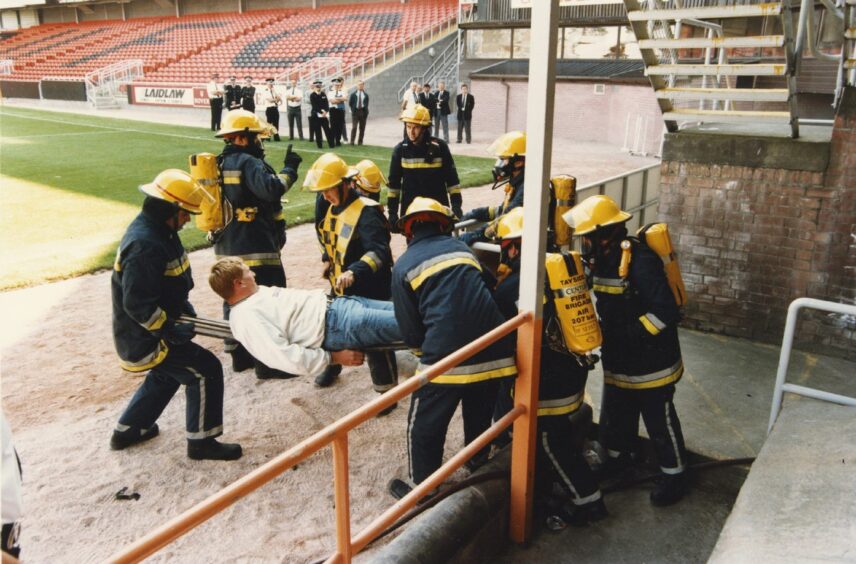 someone on a stretcher surrounded by firefighters during the mock test at Dundee United's Tannadice Park 