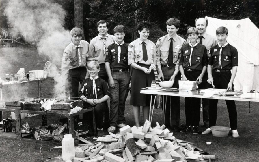 Leaders look on during this demonstration of backwoods cooking from the boys of the 25th Dundee Scout Group at Camperdown Park in June 1985.