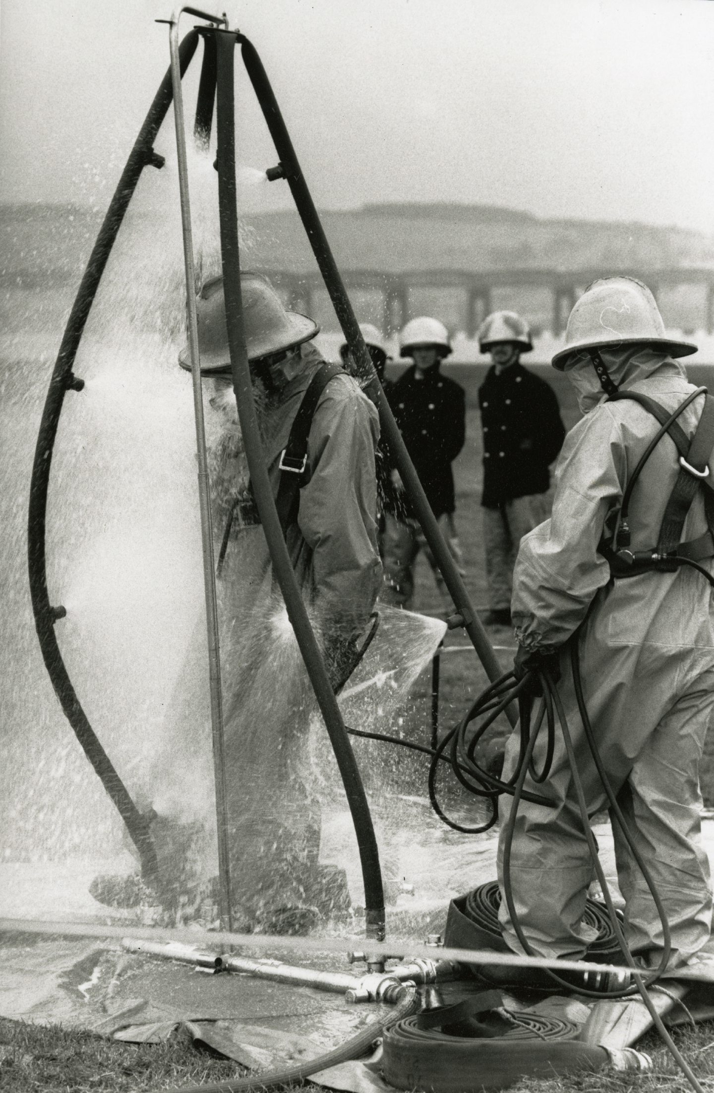 A firefighter being sprayed with water to decontaminate following a disaster simulation exercise at Dundee Airport in October 1989. The Tay Bridge is visible in the background