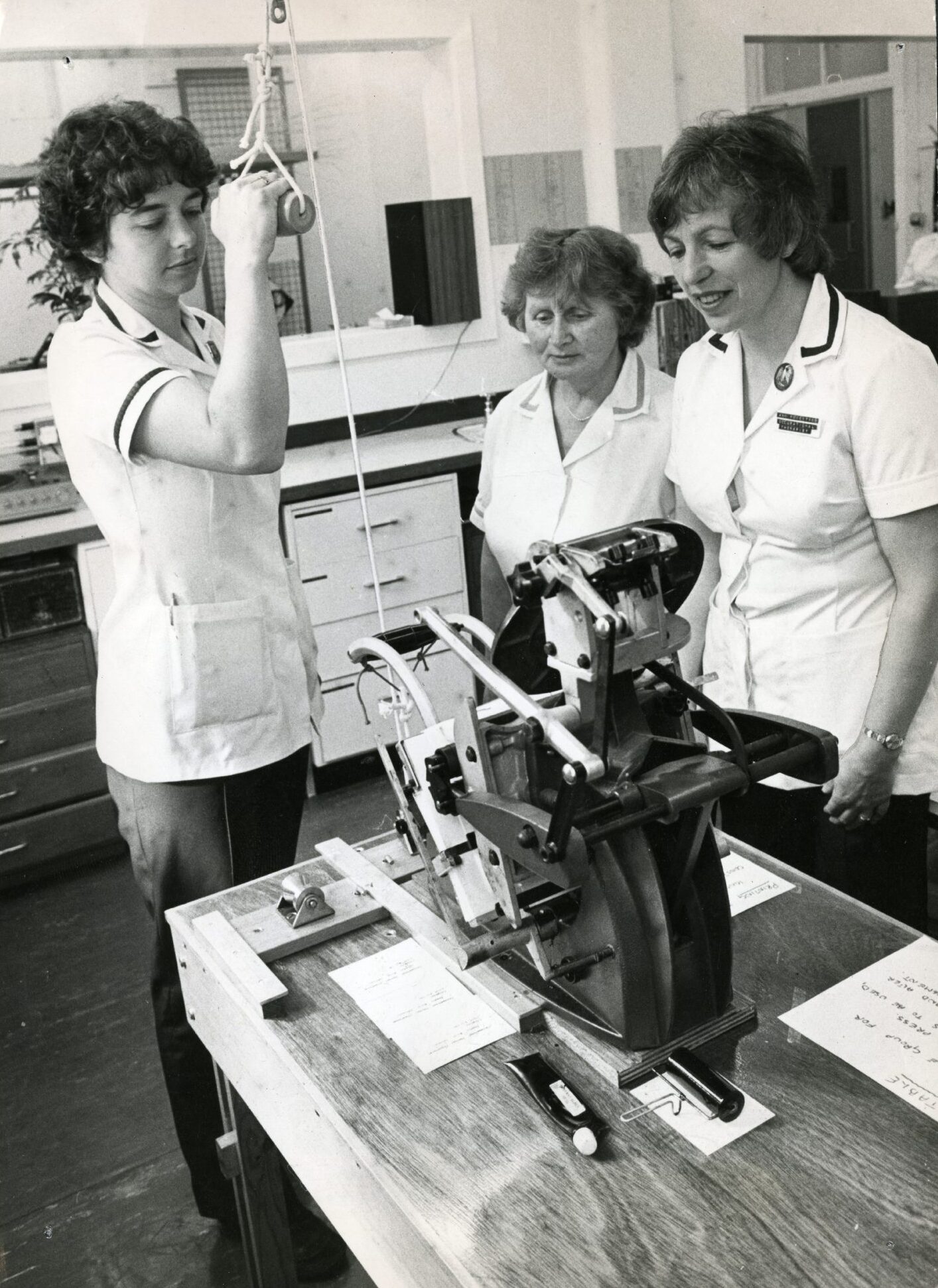 two nurses look on as one demonstrates equipment at the occupational therapy department. 