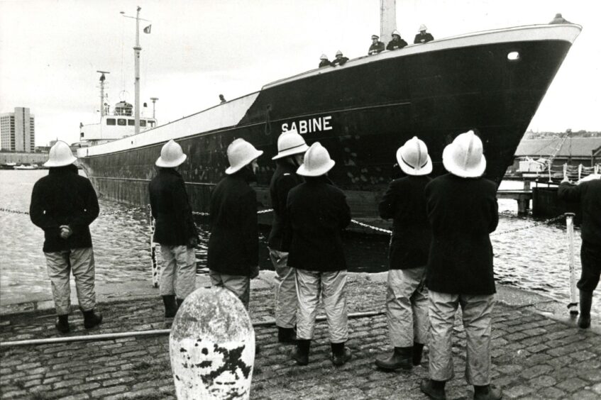  firefighters standing at the dockside and on the ship