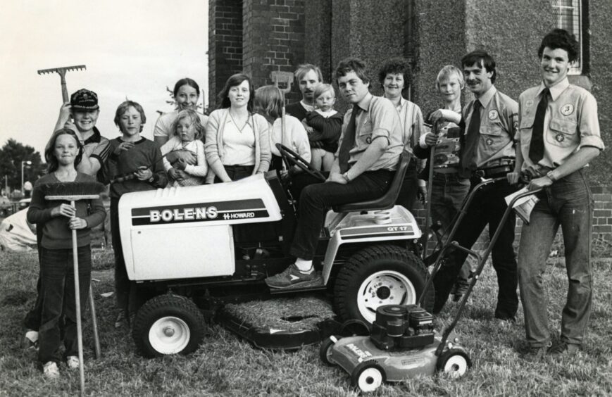 Scouts and helpers who cut the grass at Mid Craigie Parish Church stand beside the ride-on lawnmower