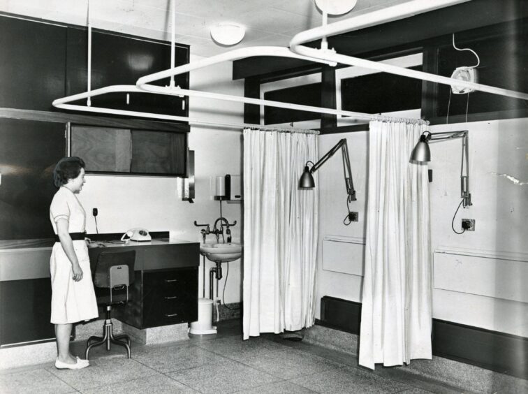 A Dundee nurse beside two curtained bays.