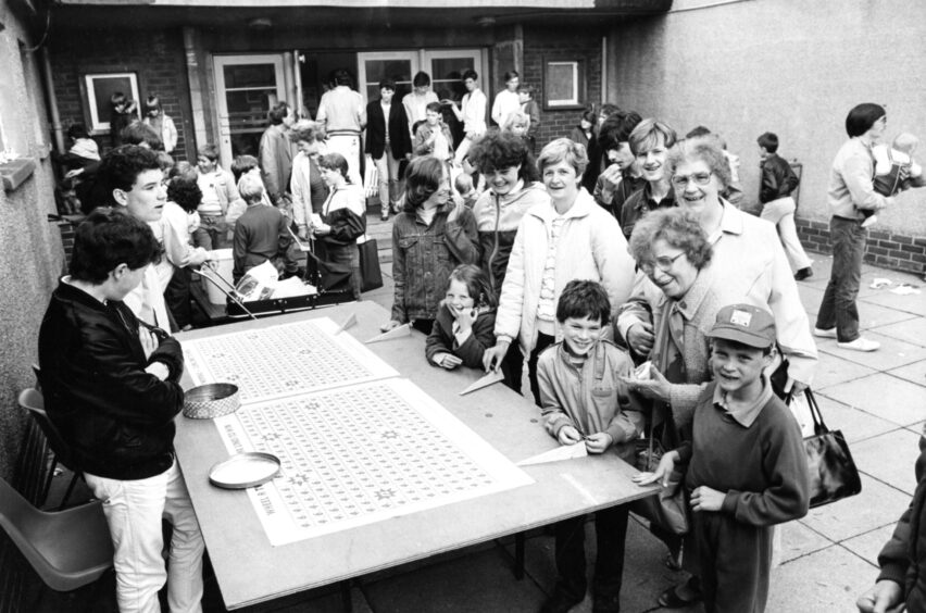 Adults and kids at the pennies stall. 