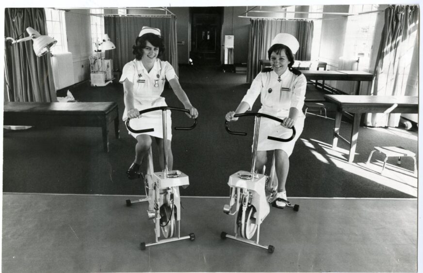 Black and white photo showing nurses on exercise bikes in hospital ward in 1979