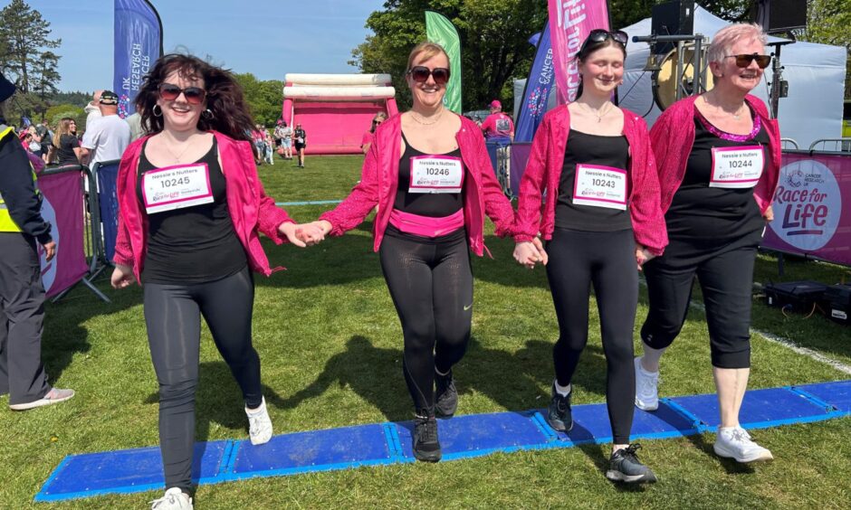 A family completes Race for Life Fife, holding hands