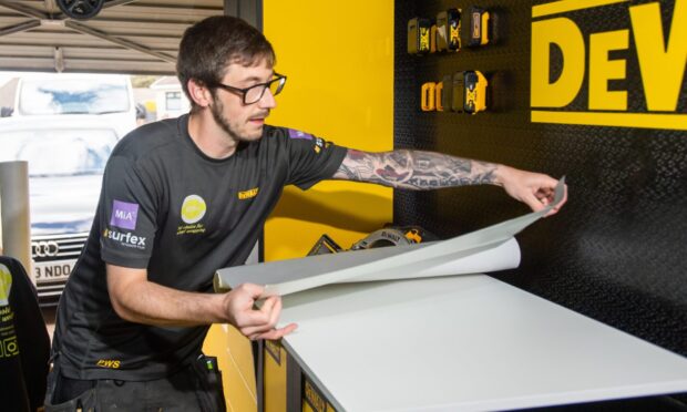Allan Anderson wrapping a door to change its appearance at his Dundee workshop. Image: Kim Cessford/DC Thomson