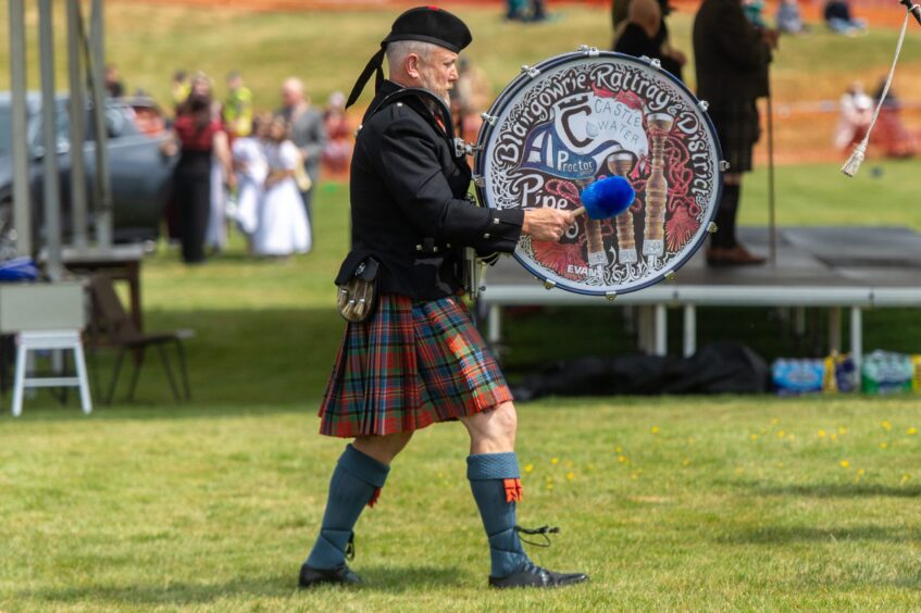 A pipe band member plays a drum