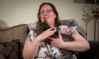 Rebecca Beasley sitting on her couch with her cat.