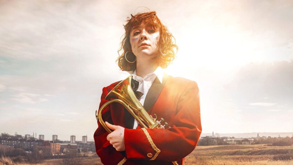 Image shows: promotional photo for the play Keli. Liberty Black poses as Keli with her tenor horn. She is wearing her red band uniform.