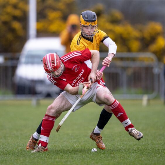 Two helmeted players playing shinty