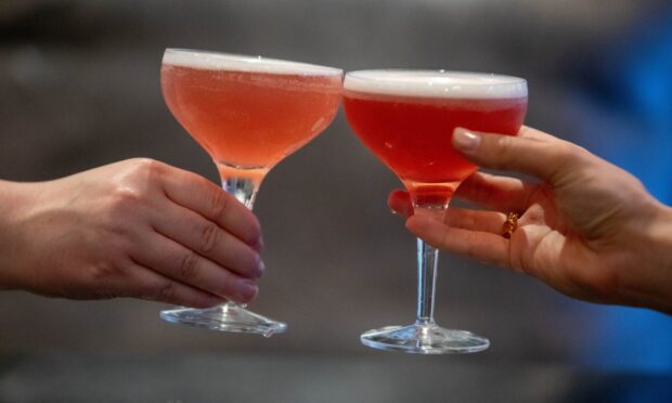 Two cocktail glasses being clinked together.