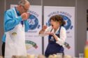 Morag Lindsay putting haggis in mouth while Jon Wilkin sniffs plate of food