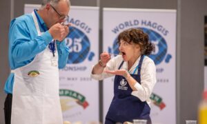 Morag Lindsay putting haggis in mouth while Jon Wilkin sniffs plate of food