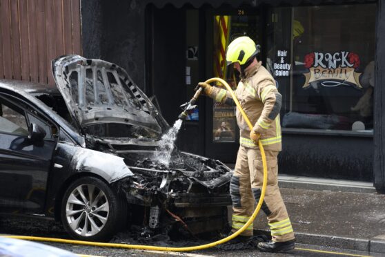 A firefighter extinguishes the car fire on Kinnoull Street in Perth. Image: Stuart Cowper