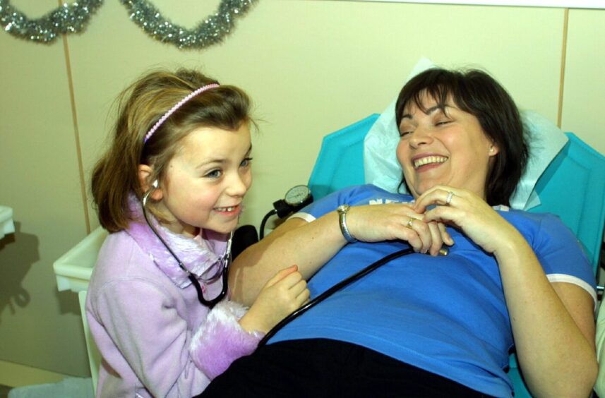 Rosie Kelly wears a stethoscope as she plays nurse with mum Lorraine.