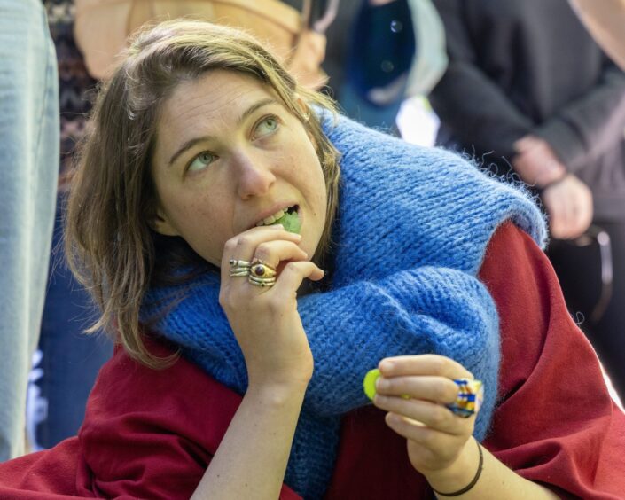 A woman with short brown hair tastes a leaf.