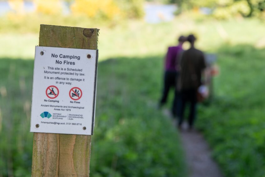 Sign on post saying 'no camping, no fires, this side is a scheduled monument protected by law'