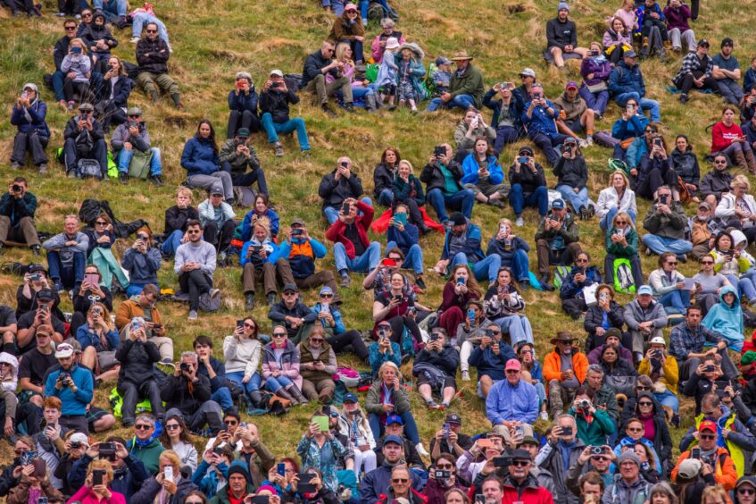 Large crowd of people on grassy slope watching games arena at Blair Castle