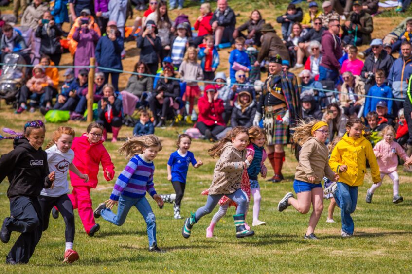 Large group of girls running watched by cheering crowd